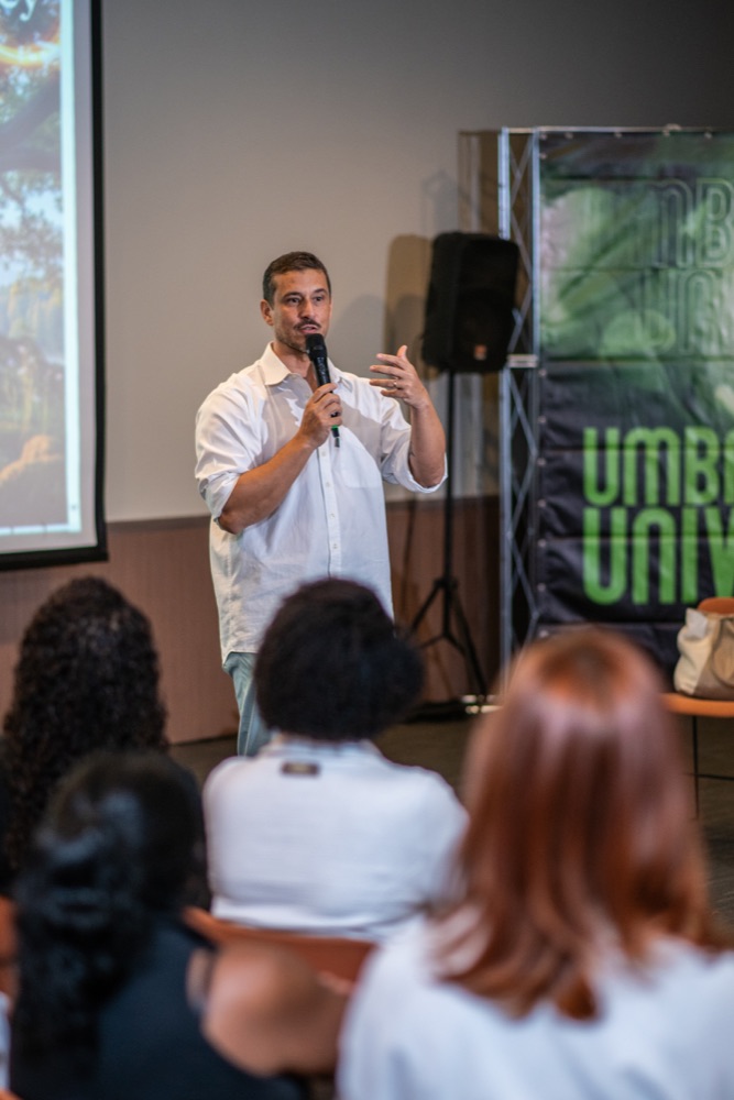 Ricardo Di Napoli falando ao microfone, banner Umbanda Natural & Universalismo ao fundo